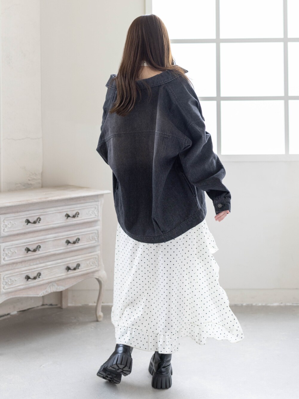 ブラック系のブーツ、ブラック系のデニムジャケット、ホワイト系のワンピースを着用したレディースの春コーディネートの3枚目の写真