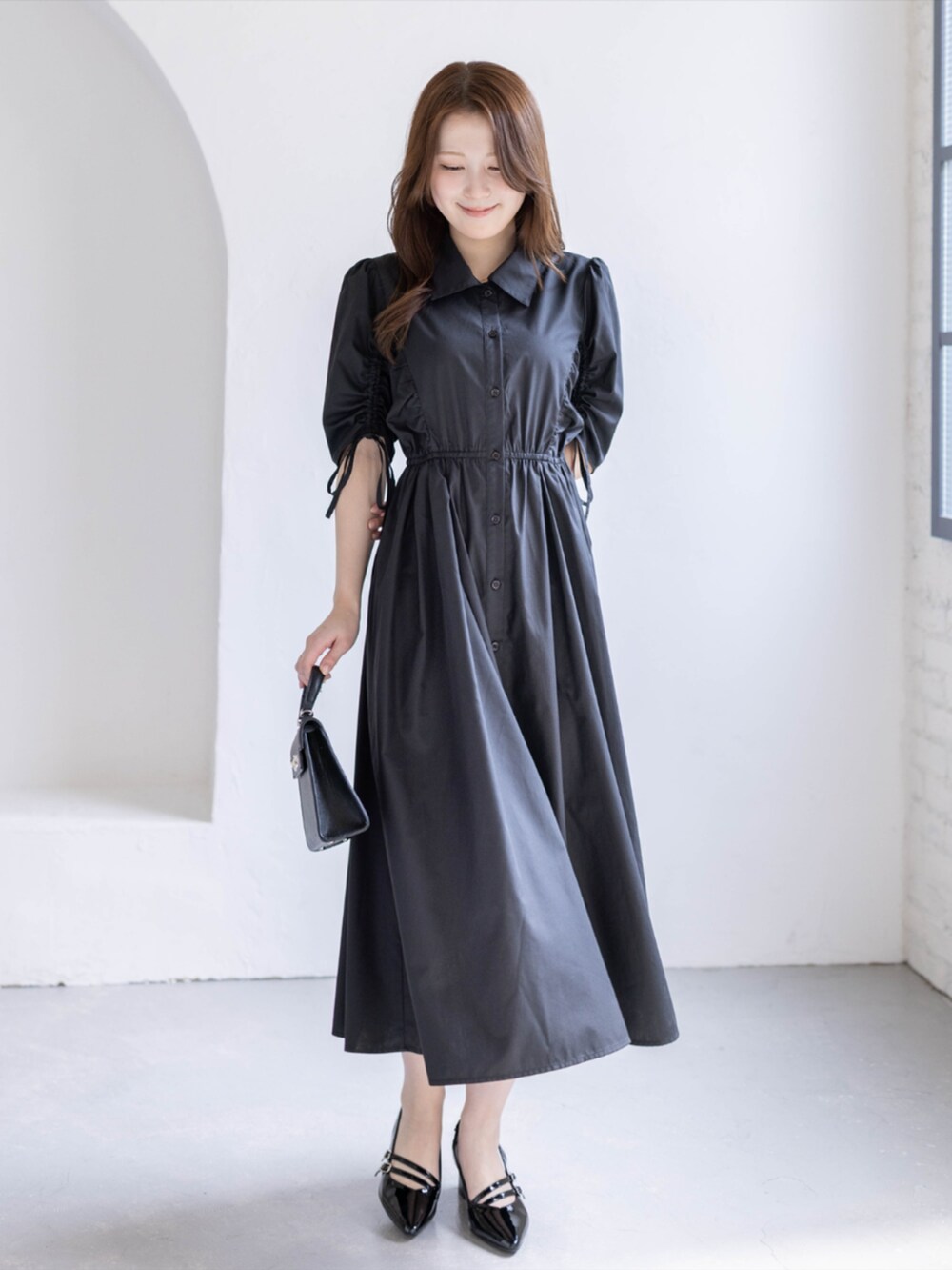 ブラック系のパンプス、ブラック系のハンドバッグ、ブラック系のワンピースを着用したレディースの春コーディネートの2枚目の写真