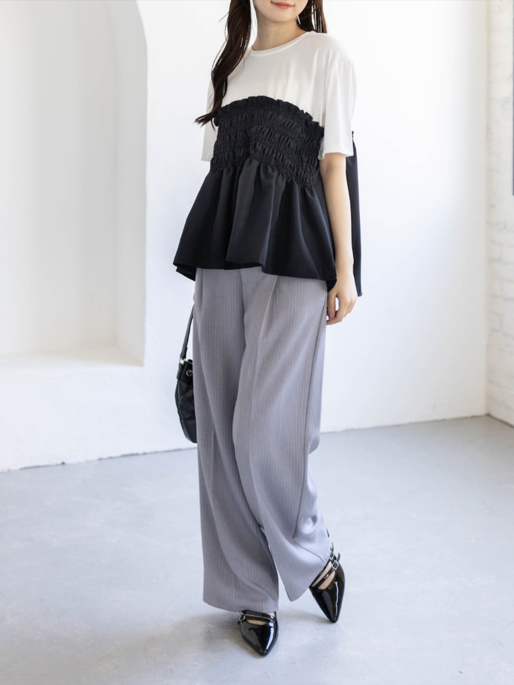 ブラック系のパンプス、グレー系のスラックス、ブラック系のハンドバッグを着用したレディースの夏コーディネートの4枚目の写真
