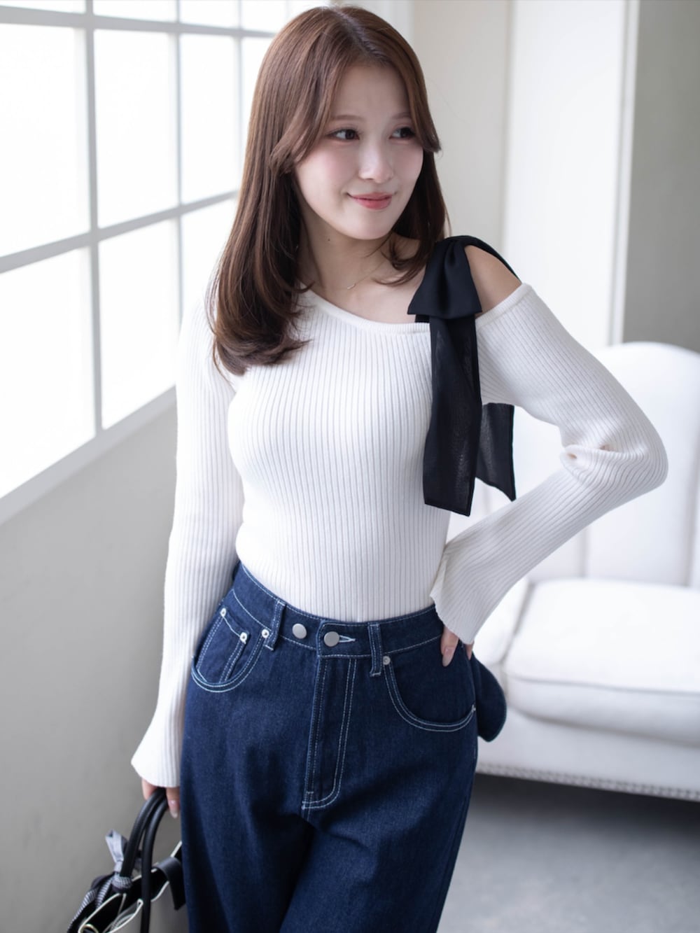 ブラック系のハンドバッグ、ブルー系のデニムパンツ、ブラック系のパンプスを着用したレディースの秋コーディネートの6枚目の写真