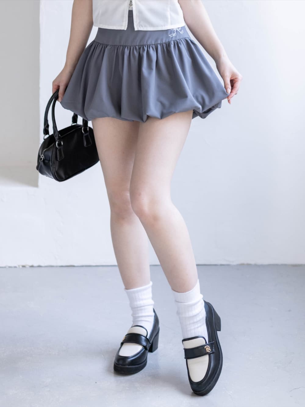 ブラック系のローファー、グレー系のスカート、ホワイト系のシャツ/ブラウスを着用したレディースの夏コーディネートの7枚目の写真