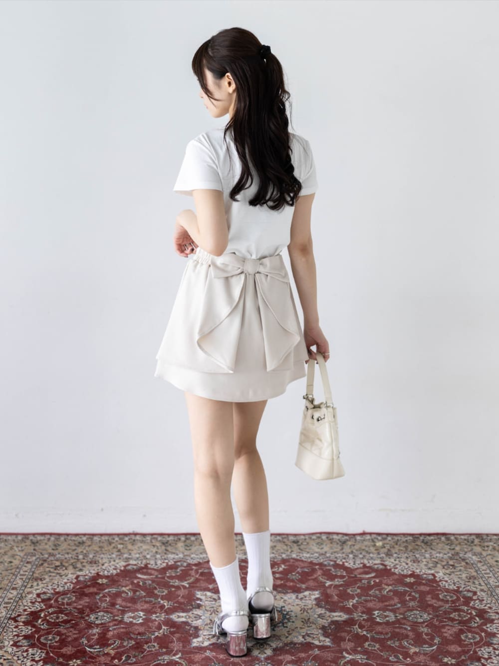 シルバー系のパンプス、ホワイト系のTシャツ/カットソー、ホワイト系のスカートを着用したレディースの夏コーディネートの2枚目の写真