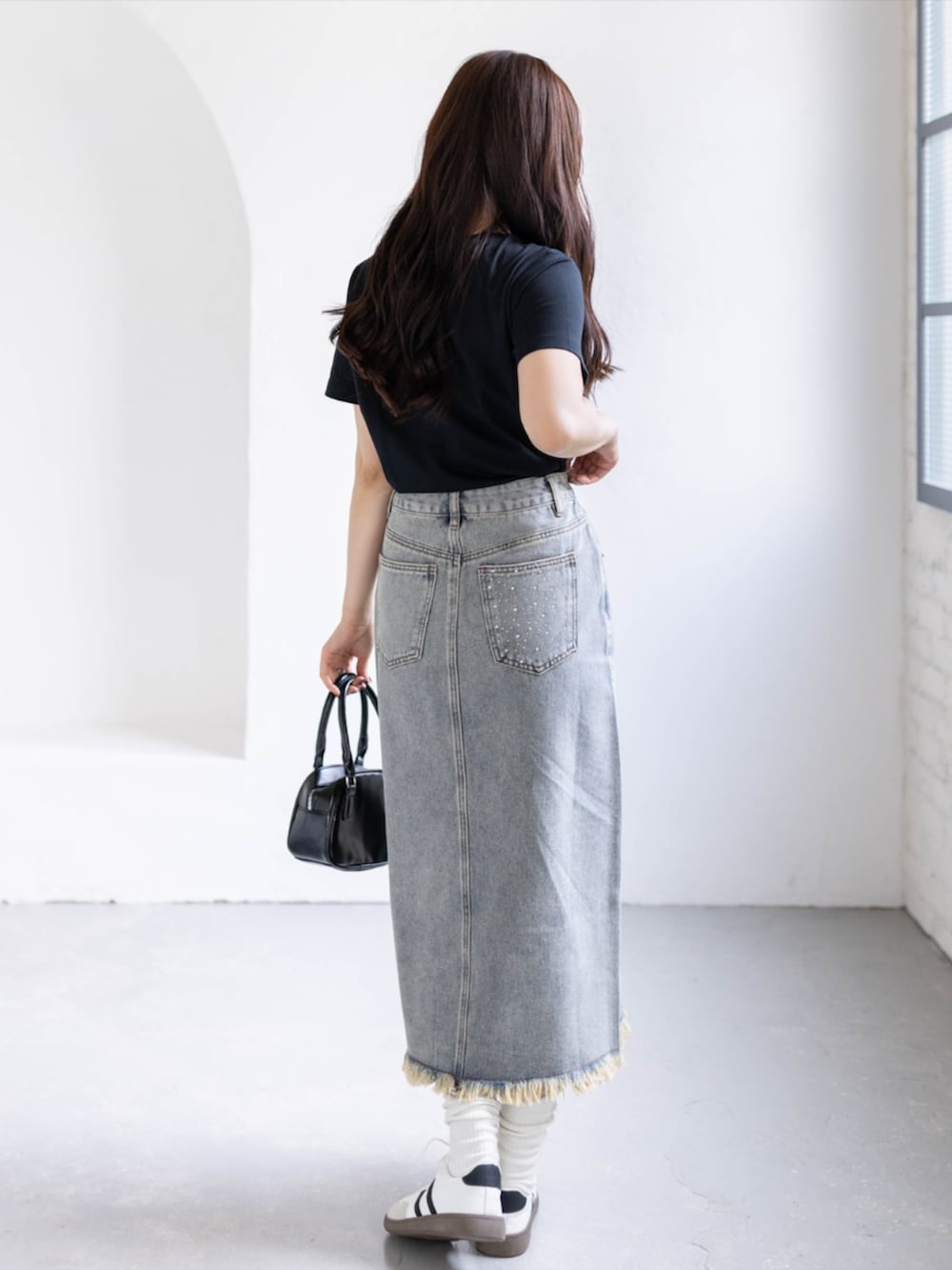 ホワイト系のスニーカー、ブルー系のスカート、ブラック系のTシャツ/カットソーを着用したレディースの春コーディネートの2枚目の写真