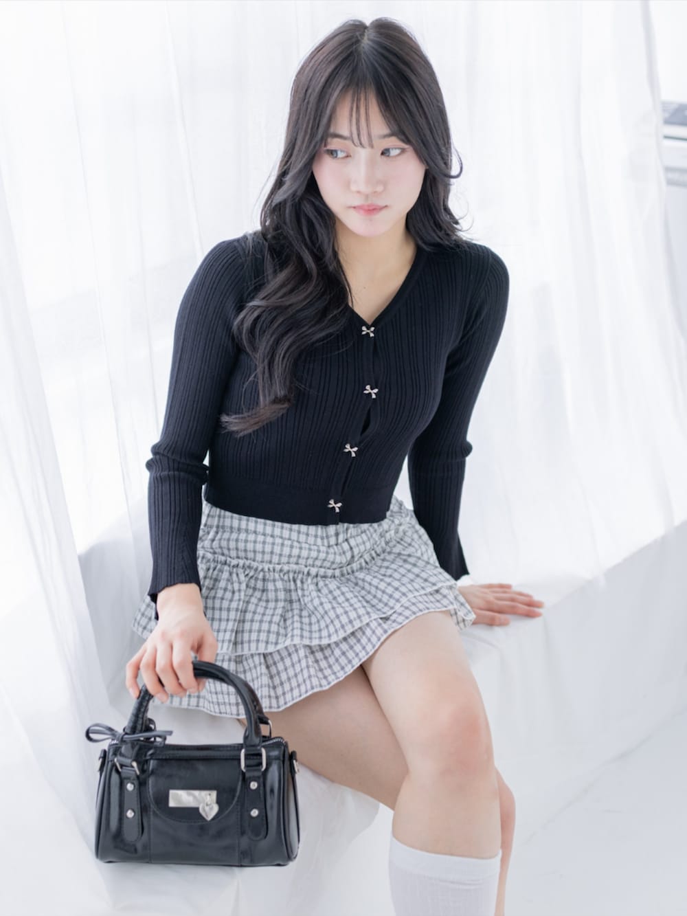 ブラック系のパンプス、ブラック系のハンドバッグ、ホワイト系のスカートを着用したレディースの夏コーディネートの5枚目の写真