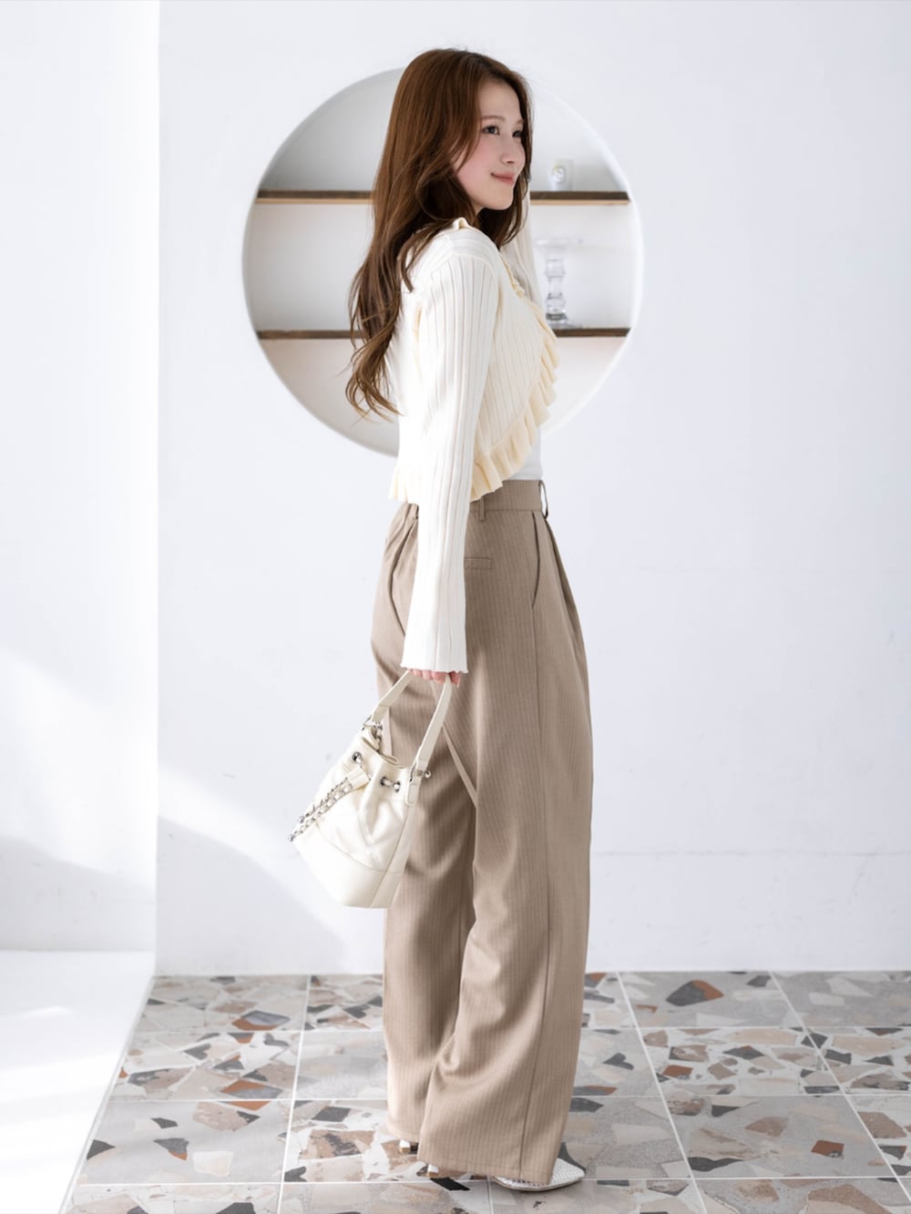 ベージュ系のその他パンツ、ホワイト系のカーディガン/ボレロ、ホワイト系のハンドバッグを着用したレディースの冬コーディネートの4枚目の写真