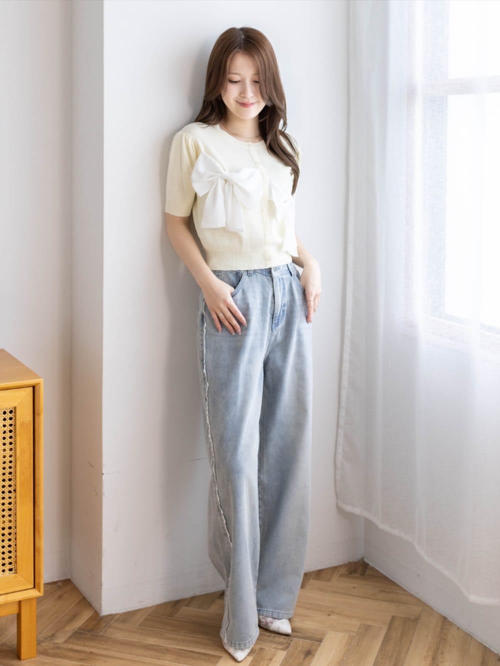 ブルー系のデニムパンツ、ホワイト系のパンプス、イエロー系のニット/セーターを着用したレディースの夏コーディネートの3枚目の写真
