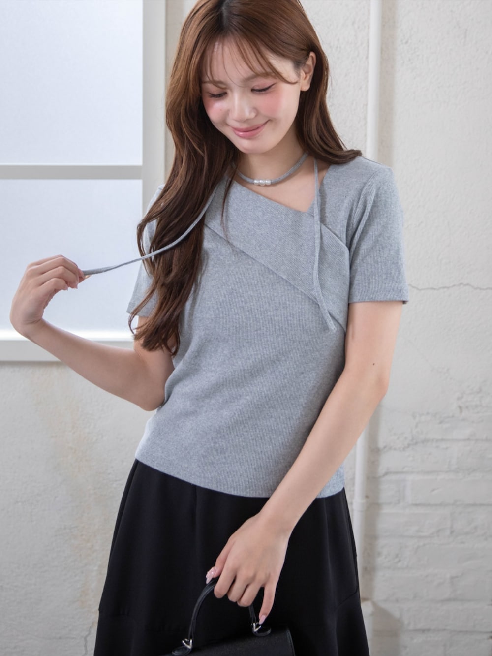 ブラック系のハンドバッグ、ブラック系のパンプス、グレー系のTシャツ/カットソーを着用したレディースの夏コーディネートの6枚目の写真