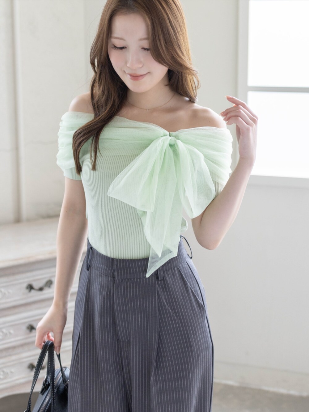 ブラック系のボストンバッグ、ブラック系のパンプス、グレー系のスラックスを着用したレディースの春コーディネートの6枚目の写真