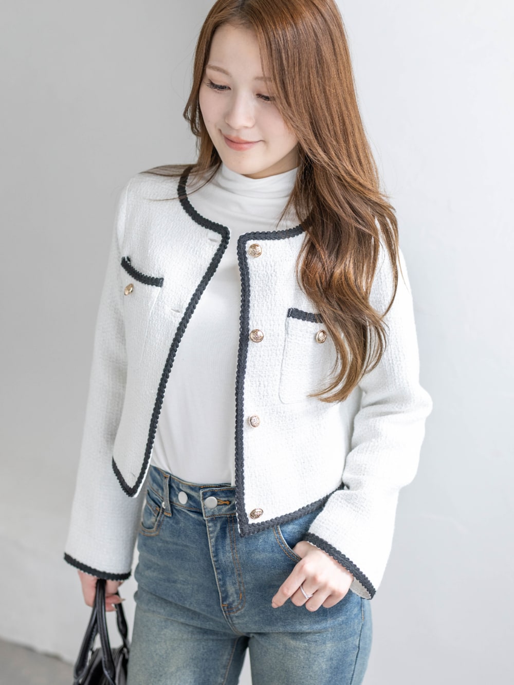 ブルー系のデニムパンツ、ブラック系のパンプス、ホワイト系のノーカラージャケットを着用したレディースの冬コーディネートの5枚目の写真