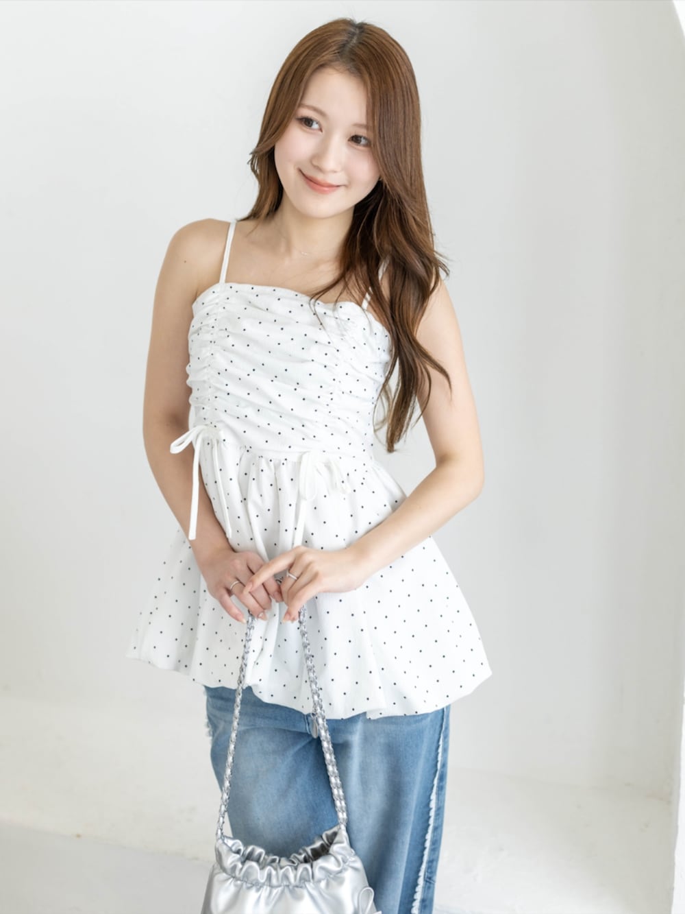 シルバー系のパンプス、ホワイト系のチュニック、ブルー系のデニムパンツを着用したレディースの春コーディネートの2枚目の写真