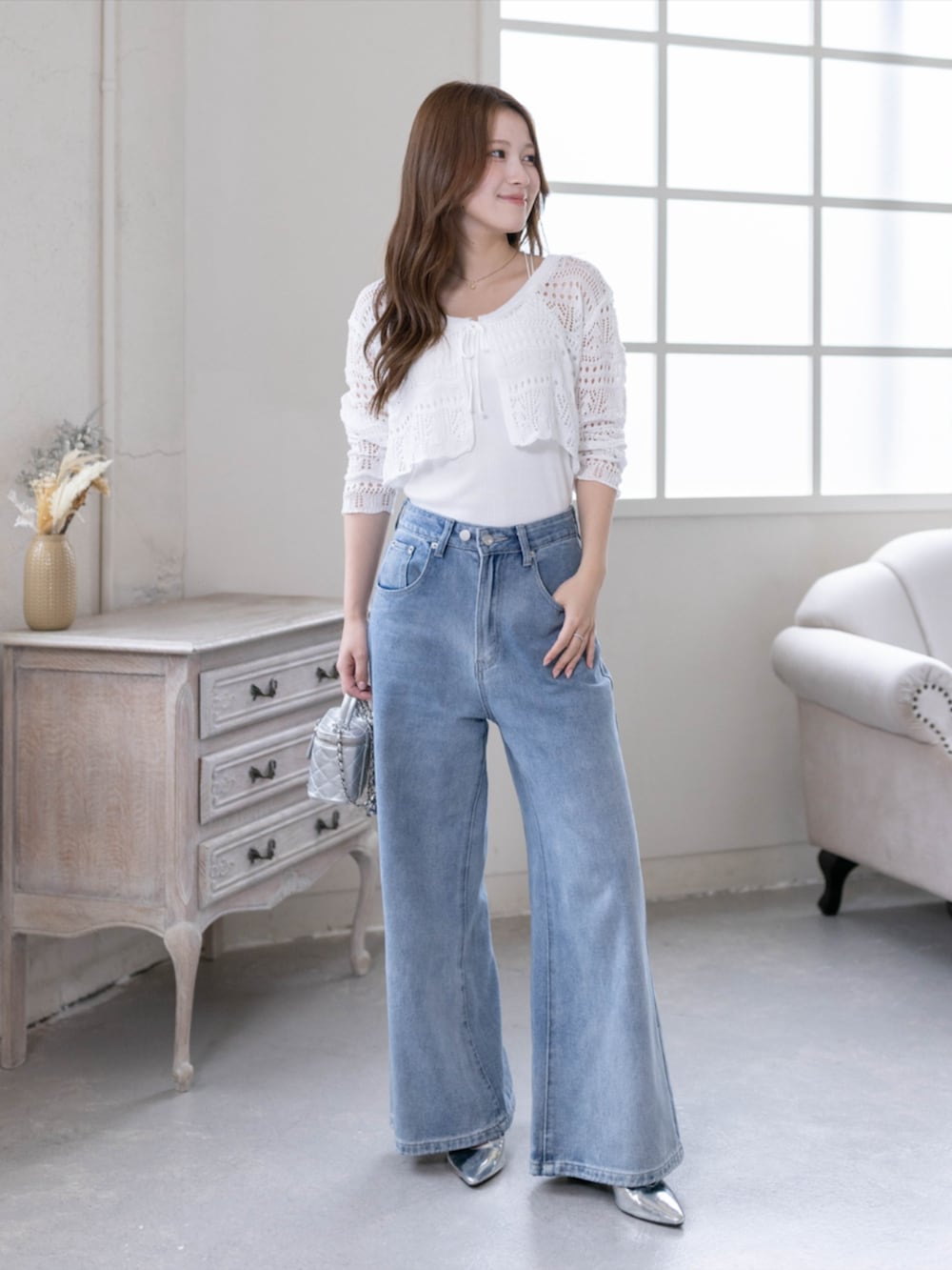 シルバー系のパンプス、ブルー系のデニムパンツ、ホワイト系のニット/セーターを着用したレディースの春コーディネートの4枚目の写真