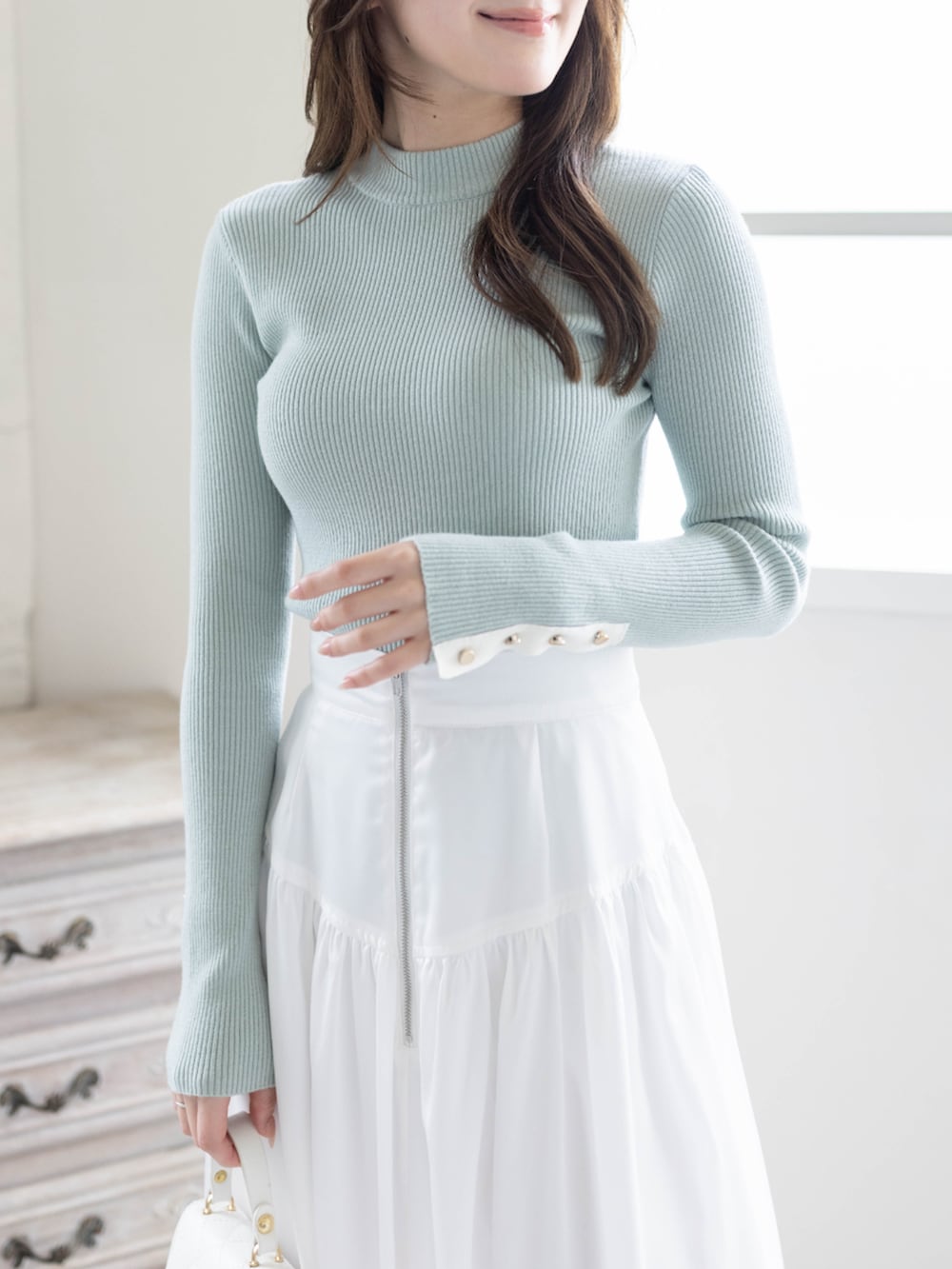 グリーン系のニット/セーター、ホワイト系のスカート、ホワイト系のパンプスを着用したレディースの春コーディネートの6枚目の写真