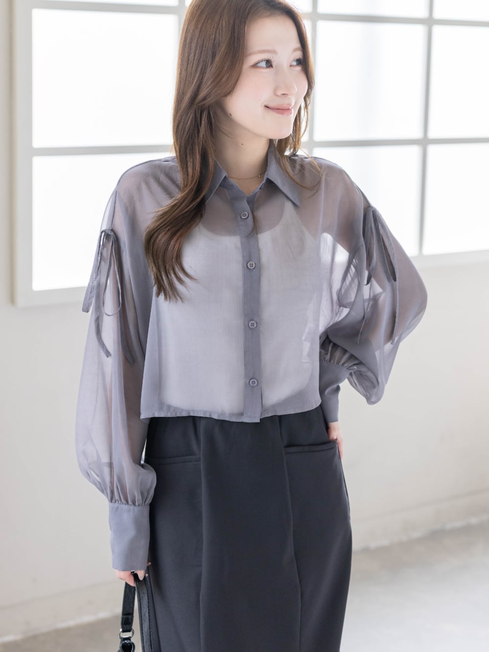 ブラック系のハンドバッグ、ブラック系のパンプス、ブラック系のスカートを着用したレディースの春コーディネートの5枚目の写真