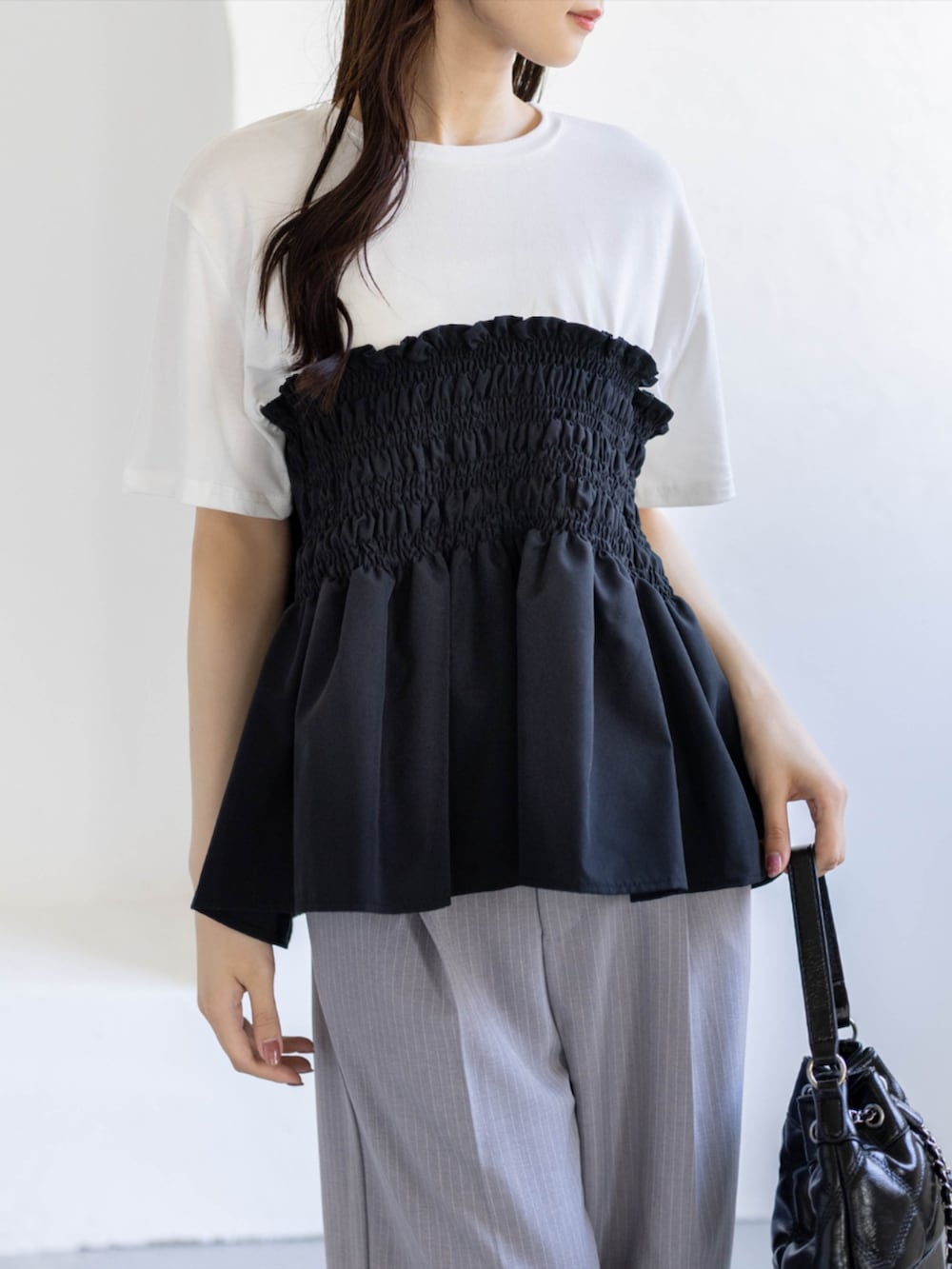 ブラック系のパンプス、グレー系のスラックス、ブラック系のハンドバッグを着用したレディースの夏コーディネートの6枚目の写真