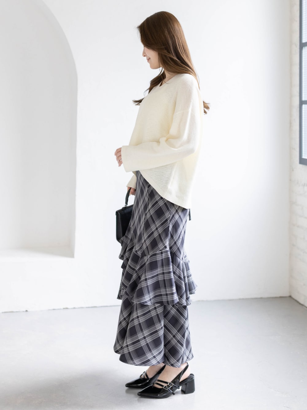 ブラック系のパンプス、ホワイト系のニット/セーター、ブラック系のスカートを着用したレディースの春コーディネートの2枚目の写真