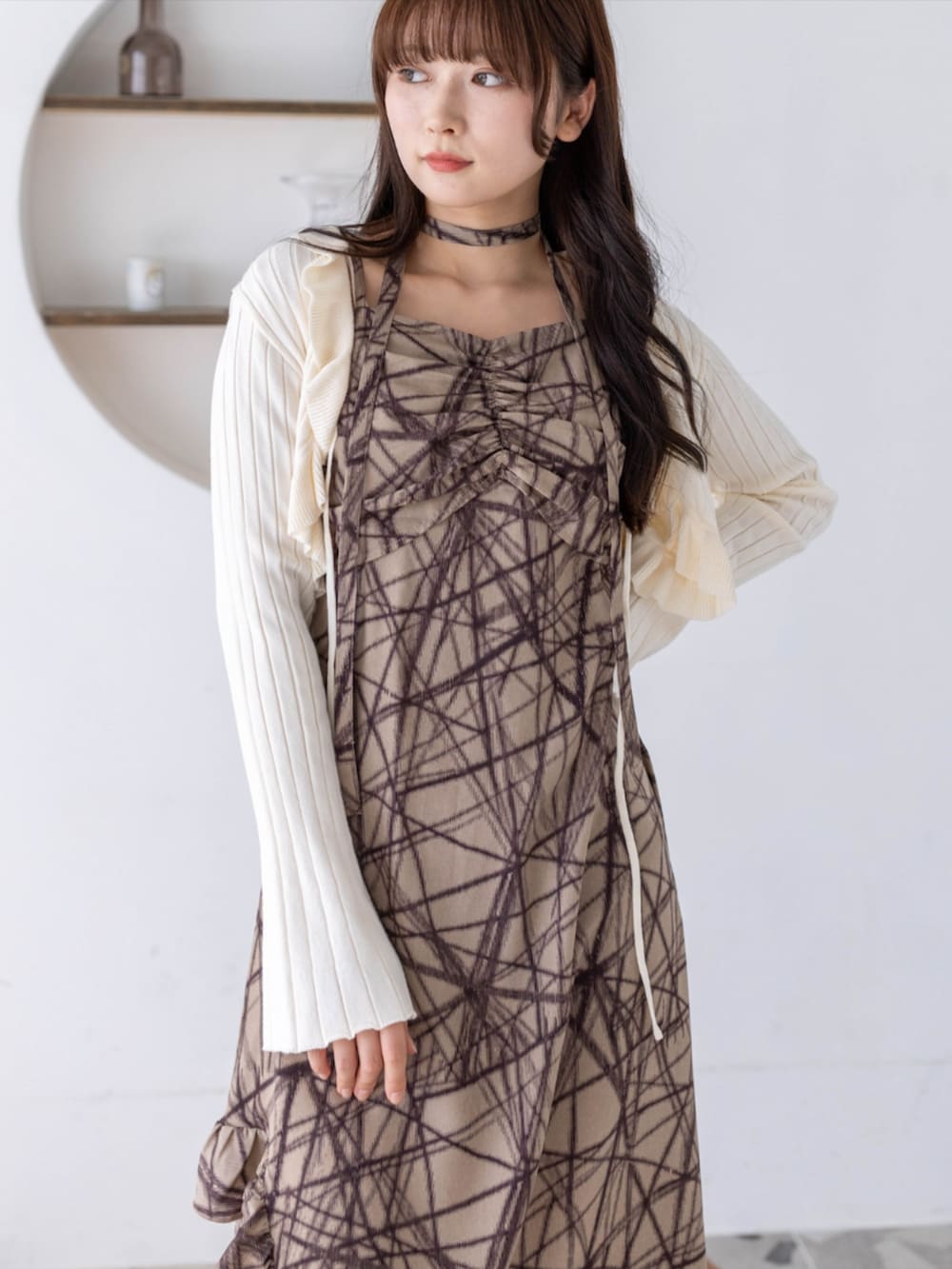 ブラック系のブーツ、ホワイト系のカーディガン/ボレロ、ベージュ系のワンピースを着用したレディースの春コーディネートの4枚目の写真