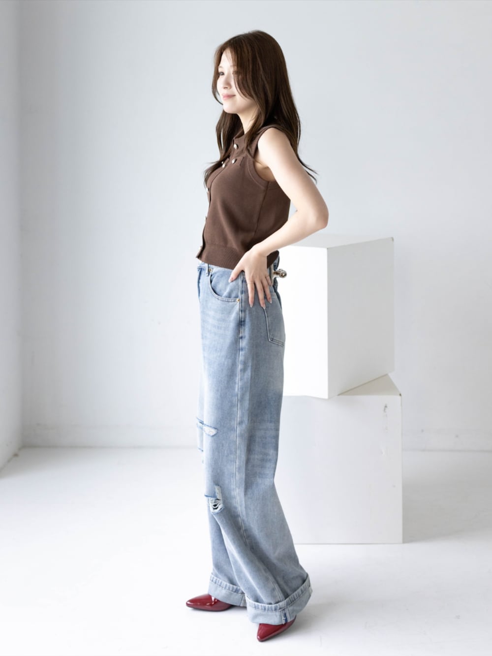 レッド系のパンプス、ブルー系のデニムパンツ、ブラウン系のニット/セーターを着用したレディースの夏コーディネートの2枚目の写真