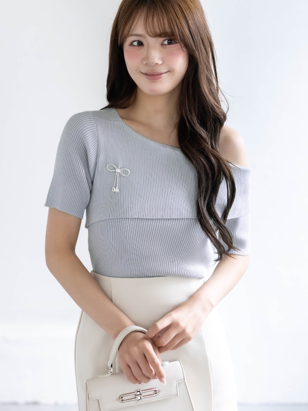 ホワイト系のスカート、ホワイト系のハンドバッグ、グレー系のニット/セーターを着用したレディースの春コーディネートの4枚目の写真