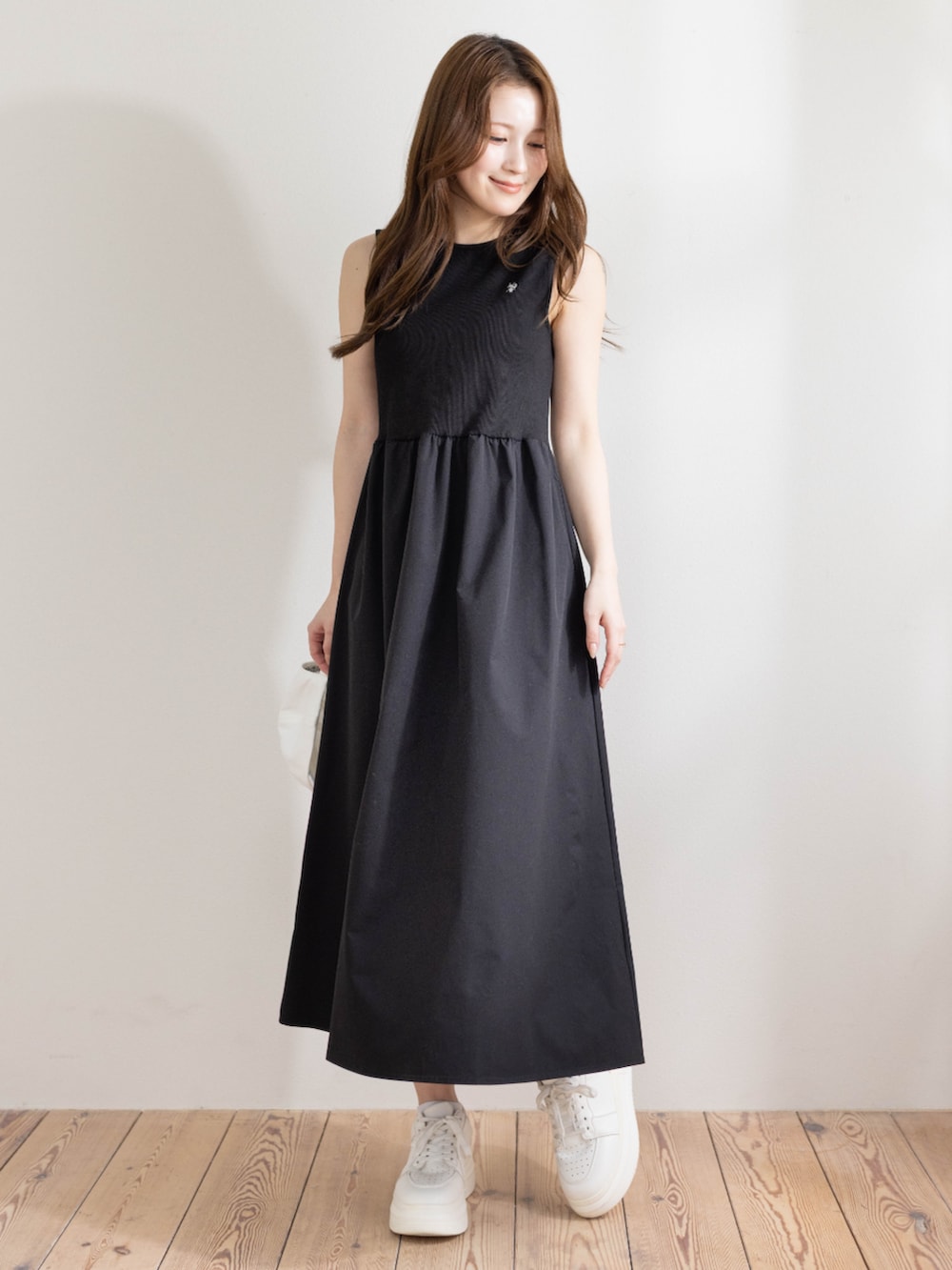 ブラック系のワンピース、ホワイト系のキャップを着用したレディースの春コーディネートの2枚目の写真