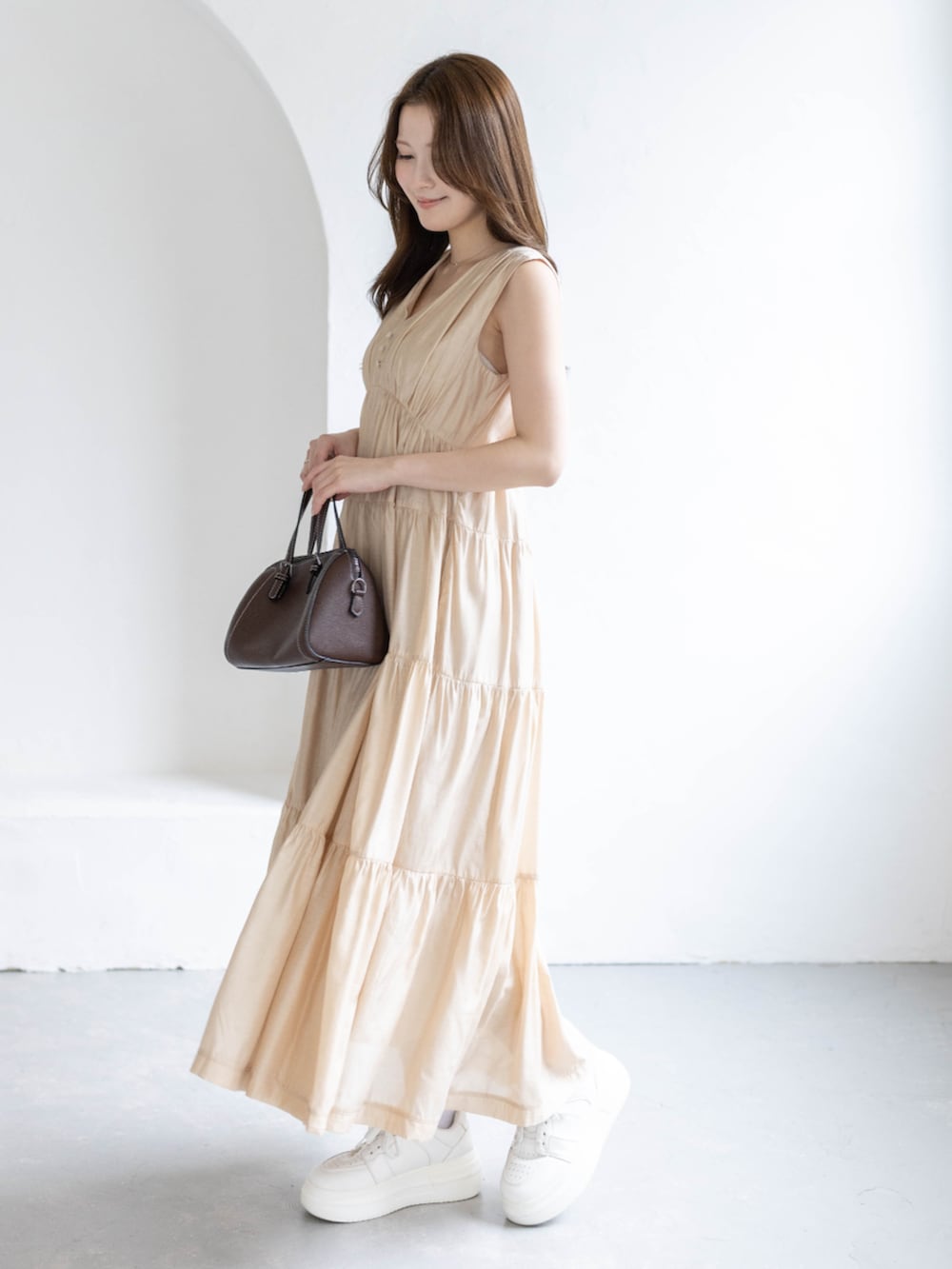 ベージュ系のワンピースを着用したレディースの春コーディネートの2枚目の写真
