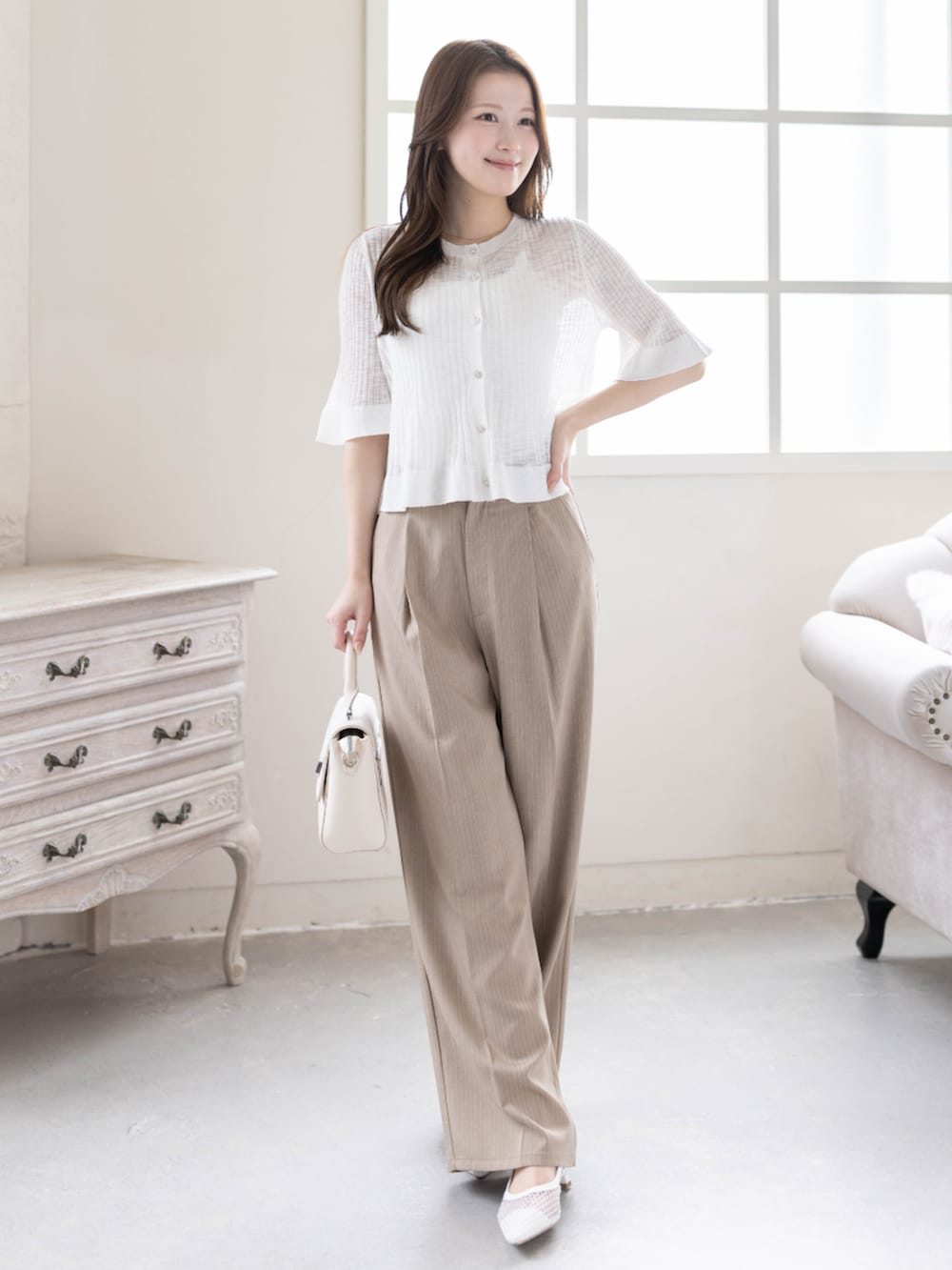 ベージュ系のスラックス、ホワイト系のパンプス、ホワイト系のカーディガン/ボレロを着用したレディースの春コーディネートの2枚目の写真