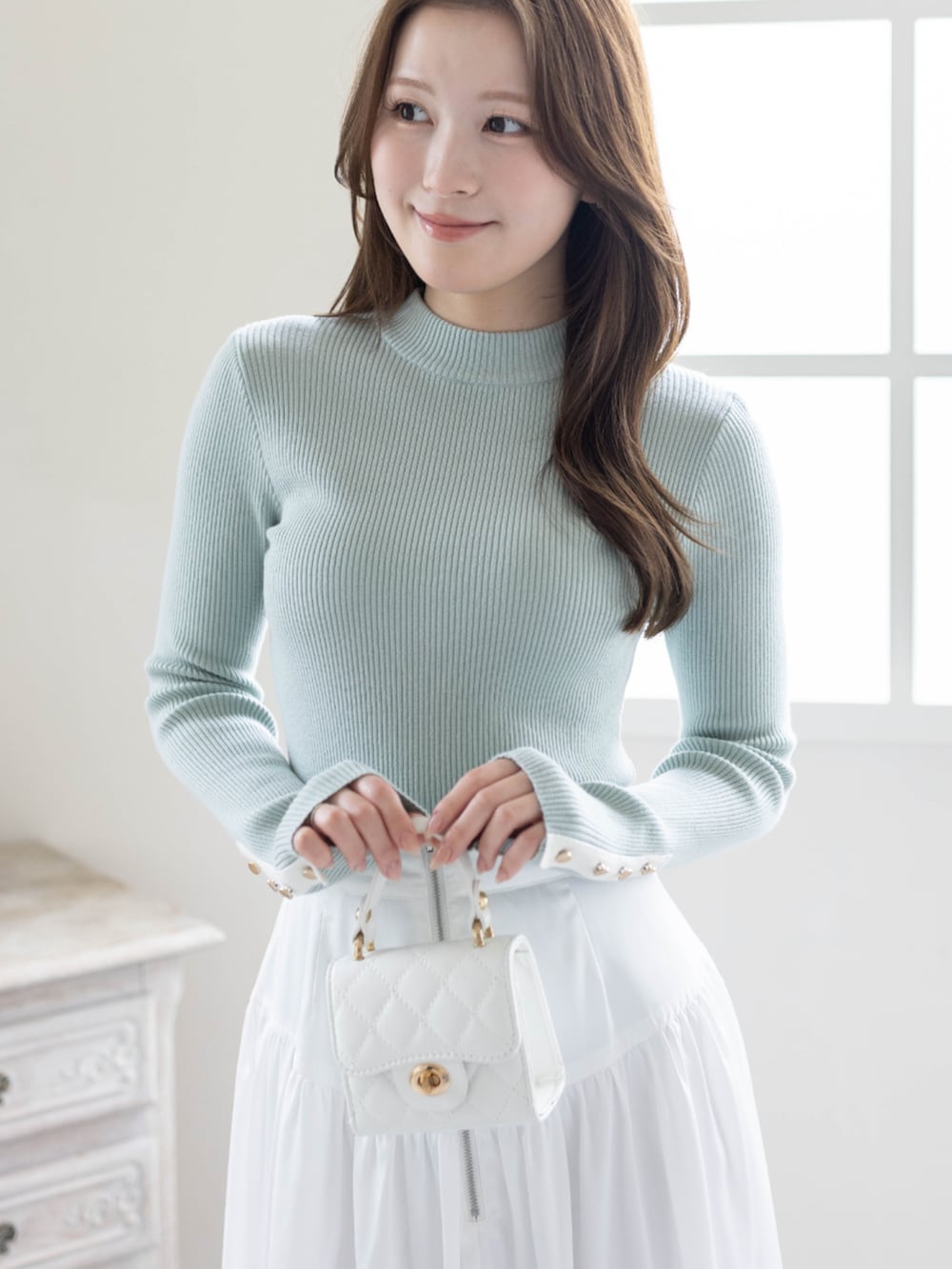 グリーン系のニット/セーター、ホワイト系のスカート、ホワイト系のパンプスを着用したレディースの春コーディネートの4枚目の写真