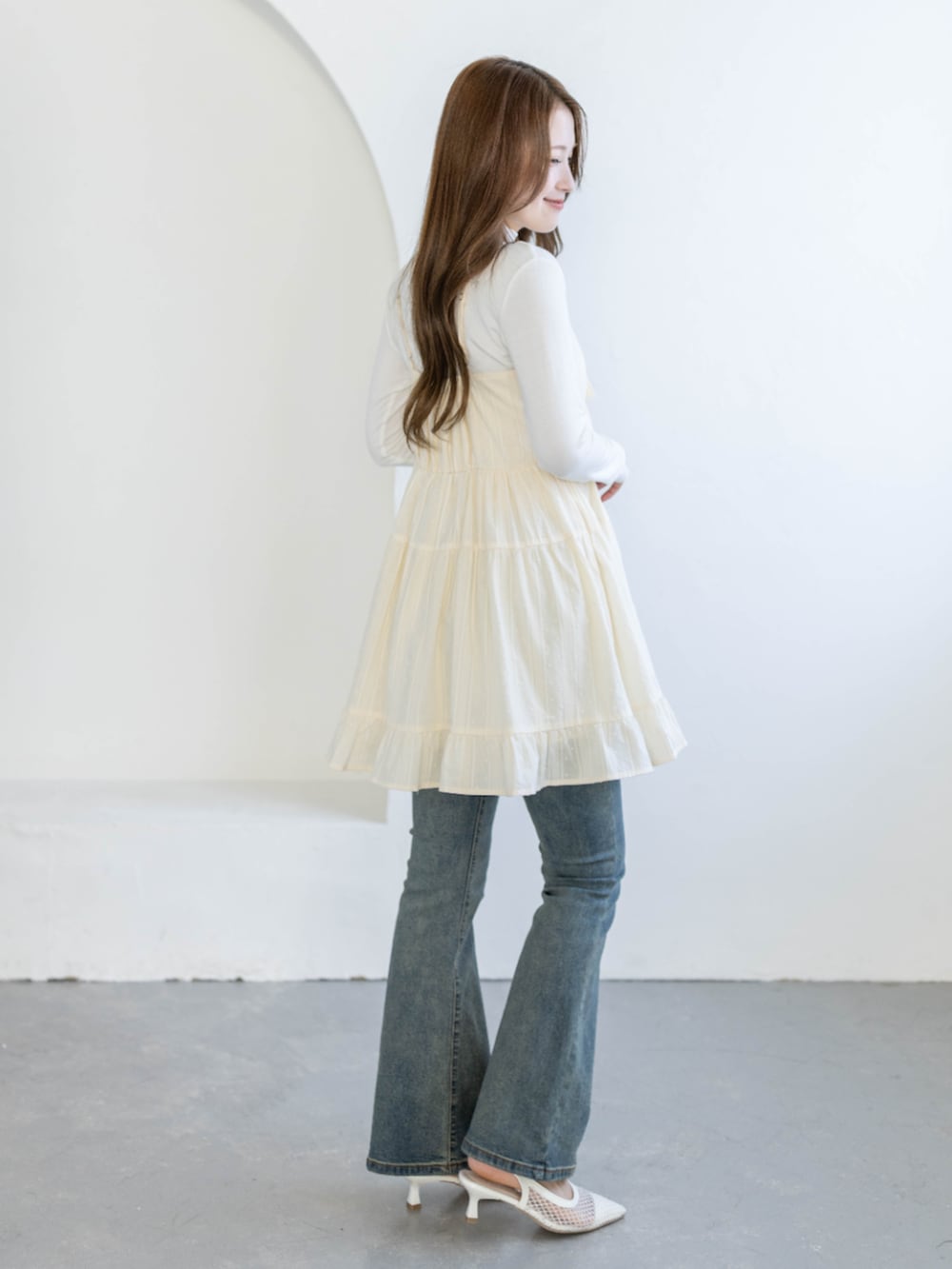 ブルー系のデニムパンツ、ホワイト系のTシャツ/カットソー、ベージュ系のワンピースを着用したレディースの春コーディネートの2枚目の写真