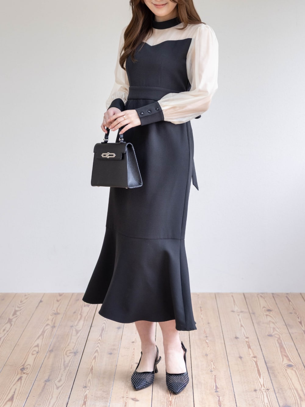 ブラック系のハンドバッグ、ブラック系のパンプス、ブラック系のワンピースを着用したレディースの春コーディネートの6枚目の写真