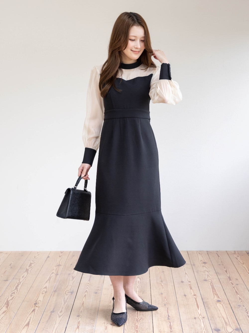 ブラック系のハンドバッグ、ブラック系のパンプス、ブラック系のワンピースを着用したレディースの春コーディネートの2枚目の写真