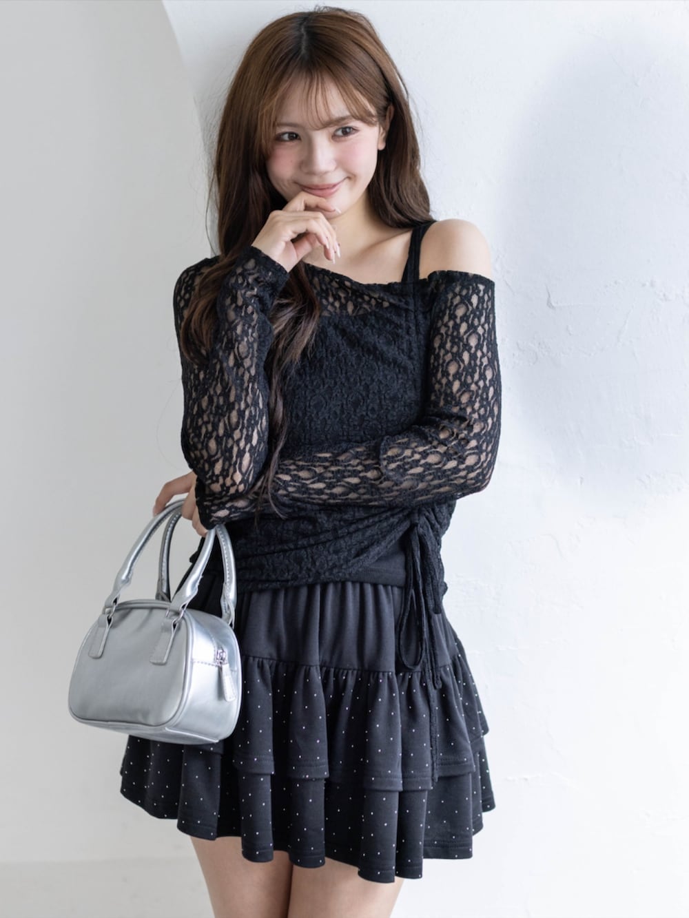 シルバー系のハンドバッグ、ブラック系のアンサンブル、ブラック系のスカートを着用したレディースの春コーディネートの4枚目の写真