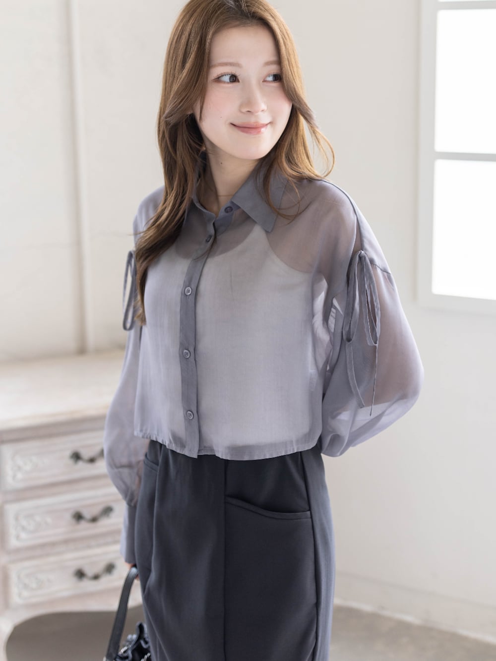 ブラック系のハンドバッグ、ブラック系のパンプス、ブラック系のスカートを着用したレディースの春コーディネートの4枚目の写真