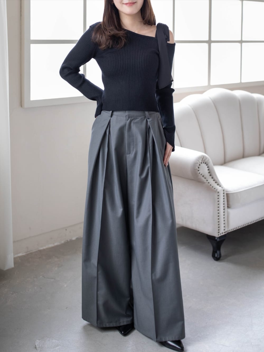 グレー系のその他パンツ、ブラック系のパンプス、ブラック系のニット/セーターを着用したレディースの秋コーディネートの2枚目の写真