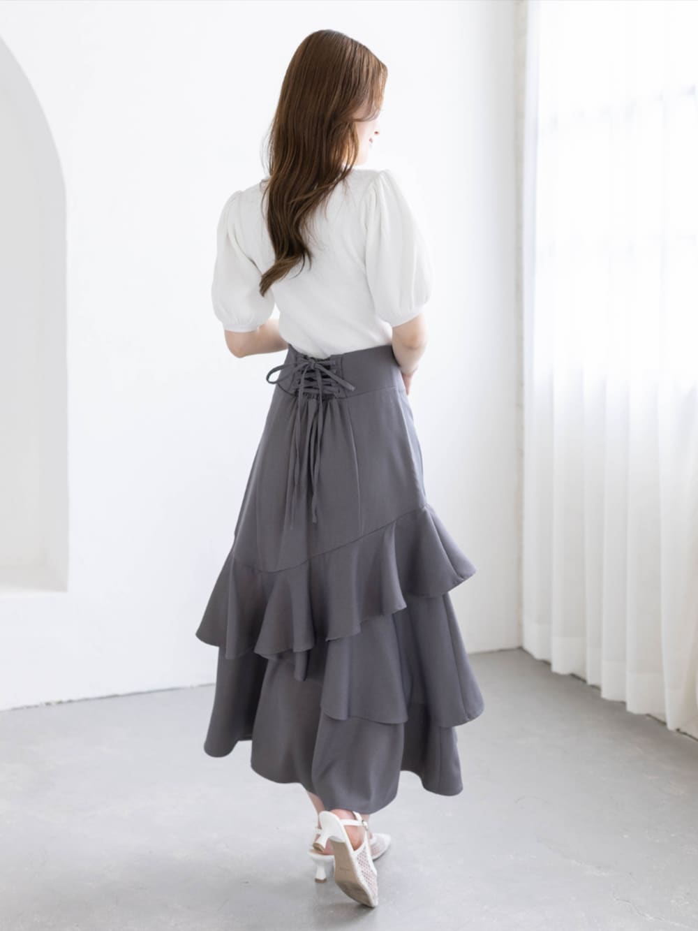 ホワイト系のパンプス、ホワイト系のニット/セーター、グレー系のスカートを着用したレディースの春コーディネートの2枚目の写真