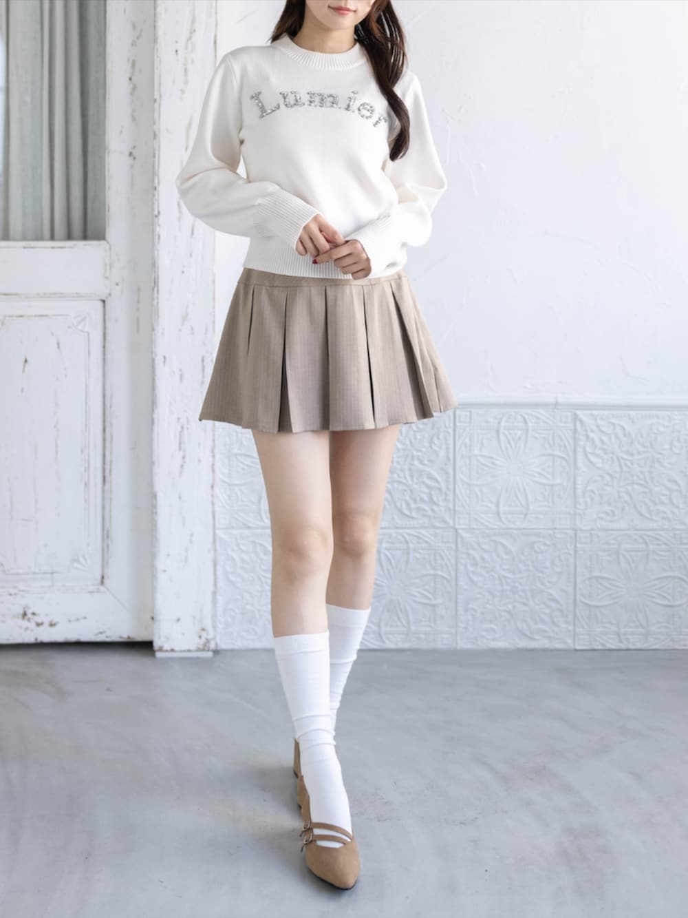ベージュ系のスカート、イエロー系のパンプス、ホワイト系のニット/セーターを着用したレディースの秋コーディネートの2枚目の写真
