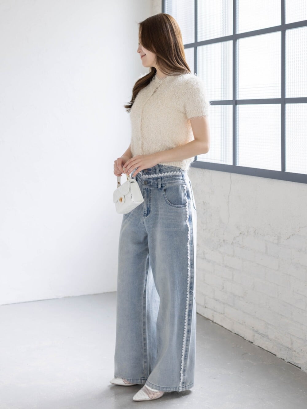 ホワイト系のパンプス、ホワイト系のカーディガン/ボレロ、ブルー系のデニムパンツを着用したレディースの春コーディネートの3枚目の写真