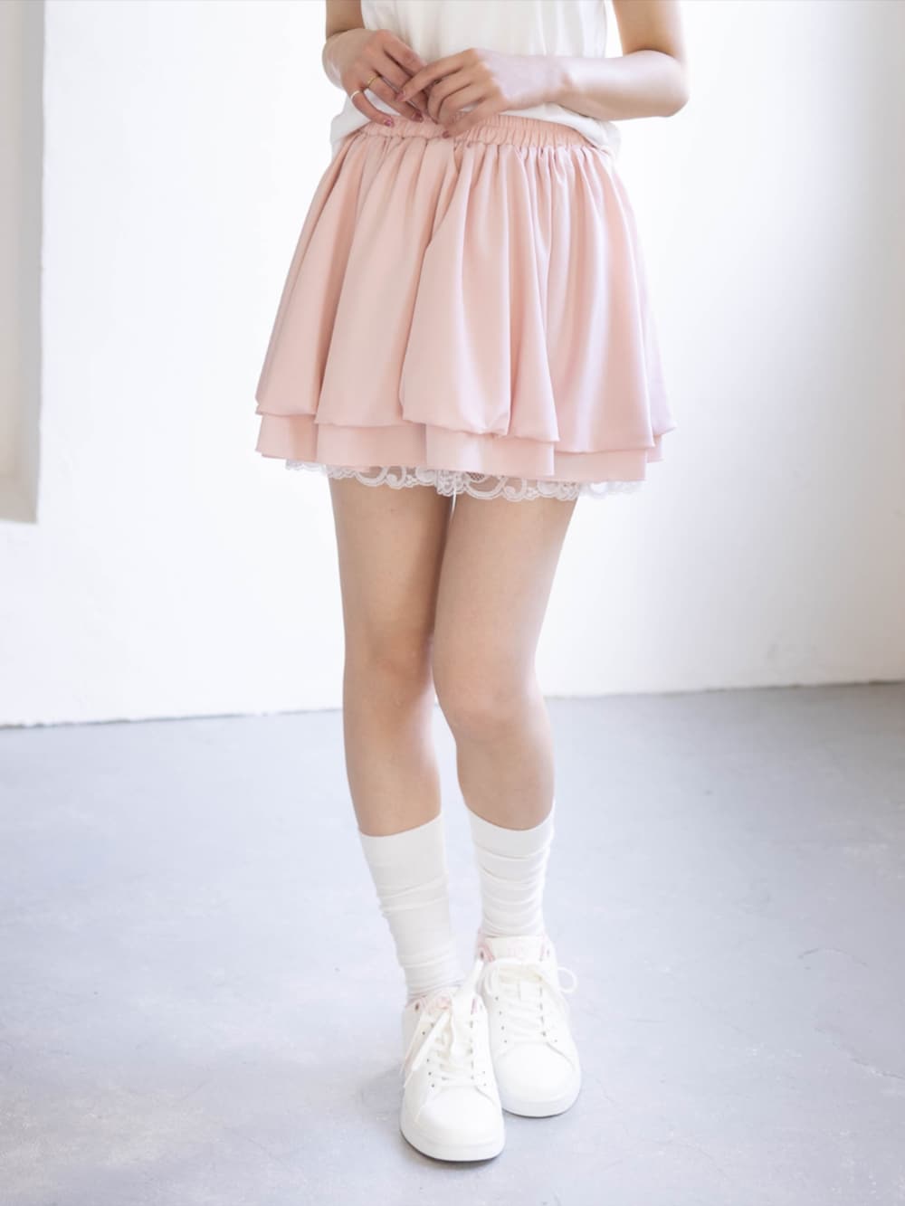 ピンク系のスニーカー、ピンク系のスカート、ホワイト系のTシャツ/カットソーを着用したレディースの夏コーディネートの3枚目の写真