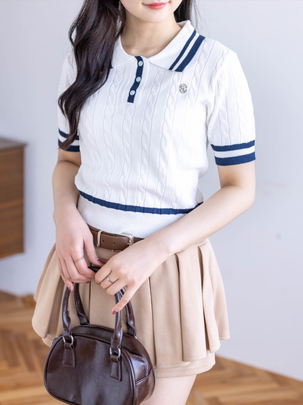 ブラウン系のハンドバッグ、ベージュ系のスカート、ブラック系のローファーを着用したレディースの春コーディネートの4枚目の写真