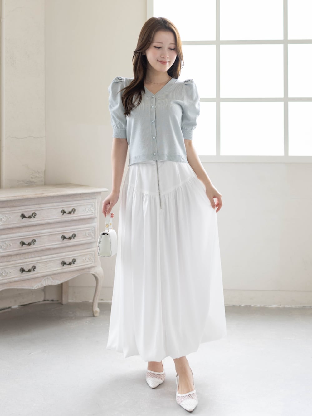 ホワイト系のスカート、ホワイト系のパンプス、グレー系のカーディガン/ボレロを着用したレディースの春コーディネートの3枚目の写真