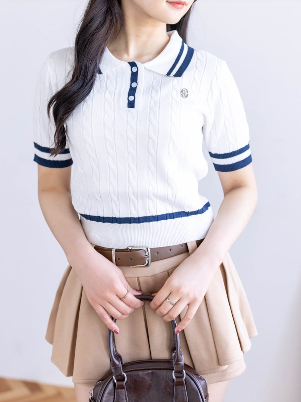 ブラウン系のハンドバッグ、ベージュ系のスカート、ブラック系のローファーを着用したレディースの春コーディネートの3枚目の写真