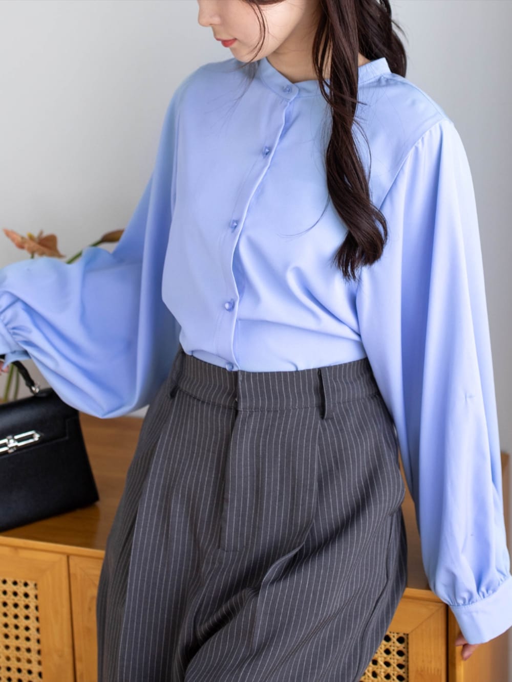 ブラック系のパンプス、ブラック系のハンドバッグ、グレー系のスラックスを着用したレディースの夏コーディネートの5枚目の写真