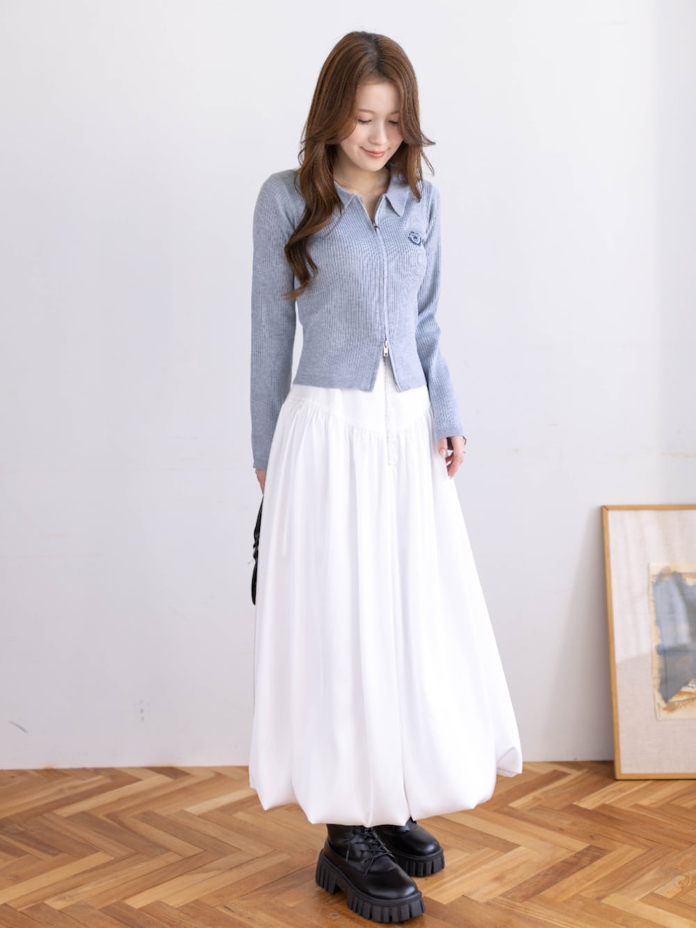 ブラック系のブーツ、グレー系のニット/セーター、ホワイト系のスカートを着用したレディースの冬コーディネートの3枚目の写真