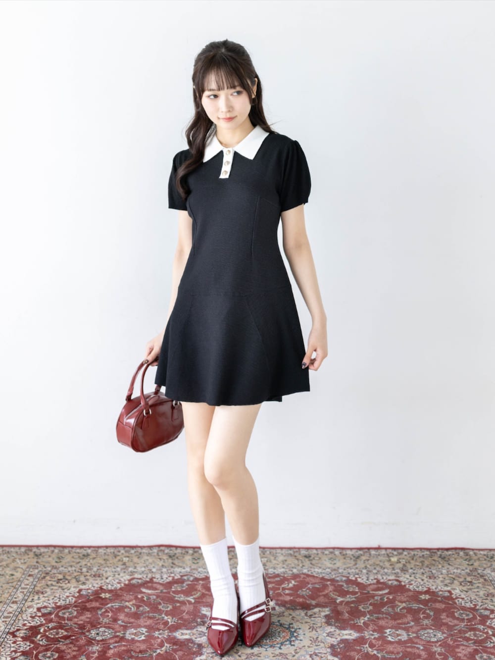 レッド系のパンプス、ブラック系のワンピースを着用したレディースの夏コーディネートの2枚目の写真