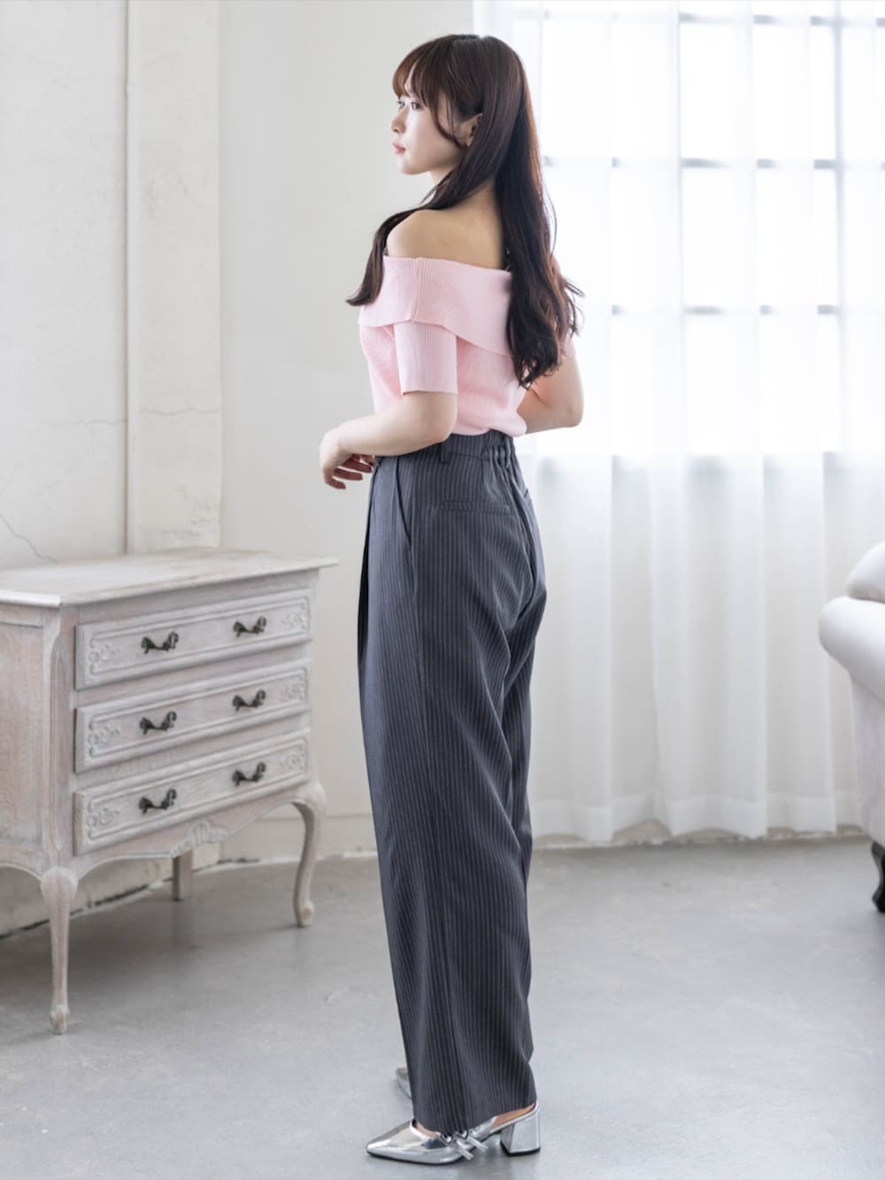 シルバー系のパンプス、ピンク系のニット/セーター、グレー系のスラックスを着用したレディースの春コーディネートの2枚目の写真