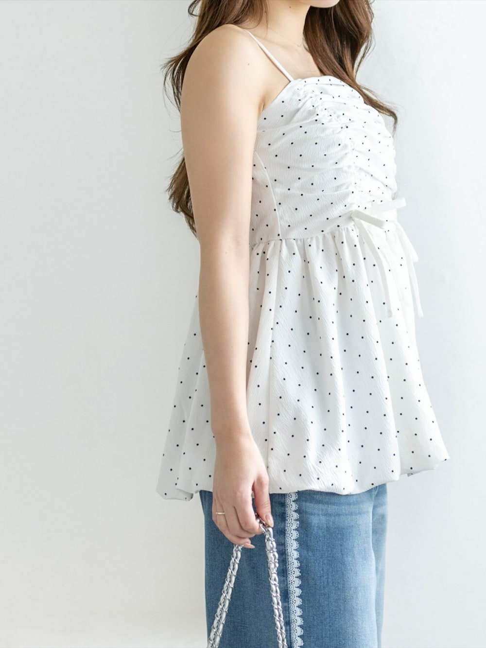 シルバー系のパンプス、ホワイト系のチュニック、ブルー系のデニムパンツを着用したレディースの冬コーディネートの3枚目の写真