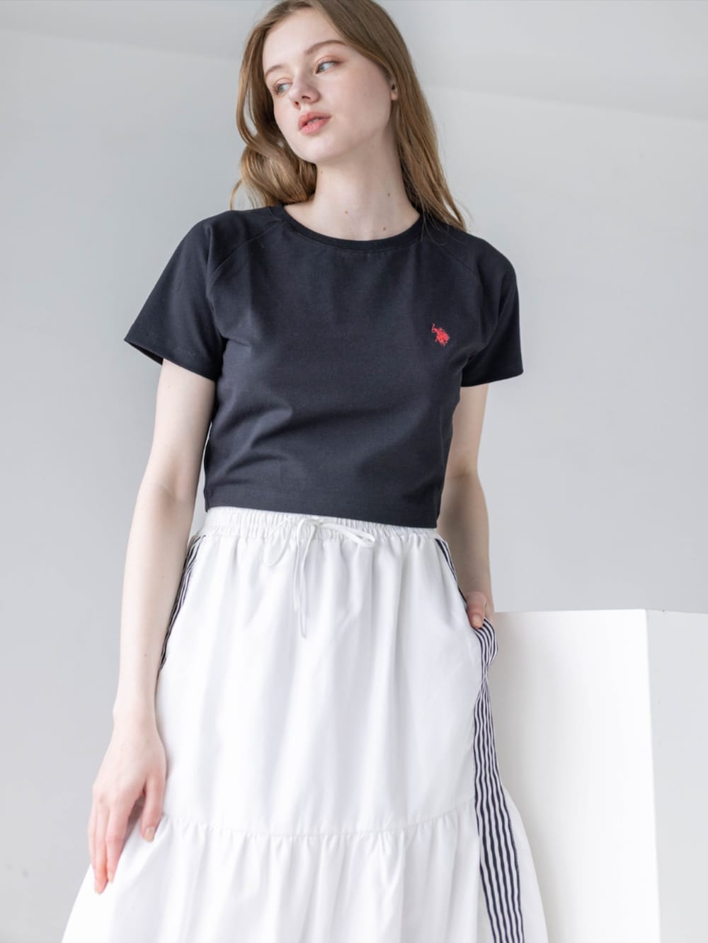 ブラック系のスニーカー、ホワイト系のスカート、ブラック系のTシャツ/カットソーを着用したレディースの夏コーディネートの6枚目の写真