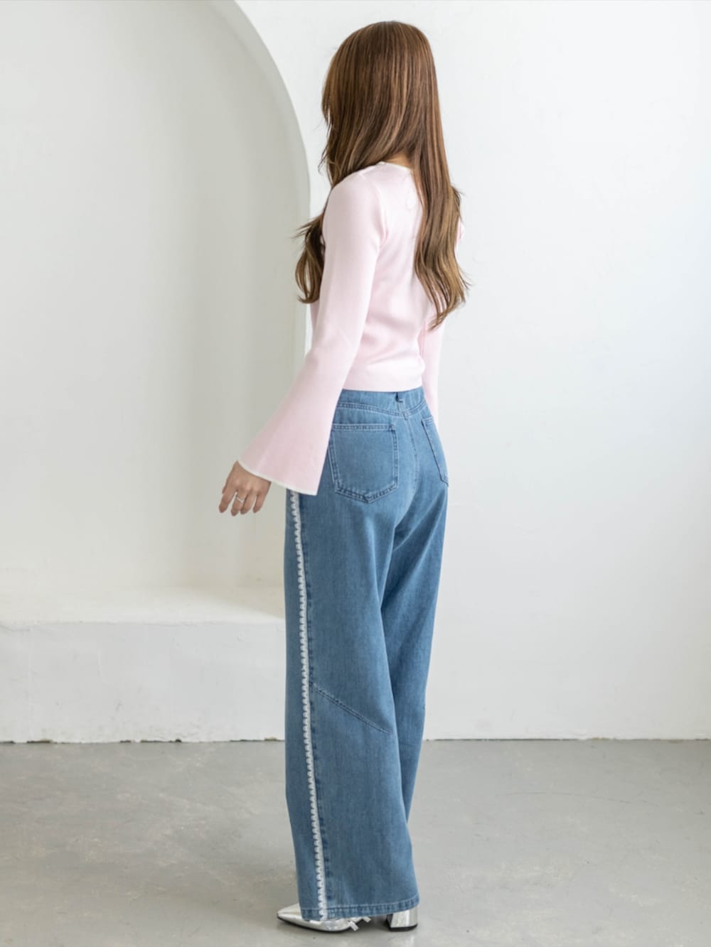 シルバー系のパンプス、ブルー系のデニムパンツ、ピンク系のニット/セーターを着用したレディースの夏コーディネートの2枚目の写真