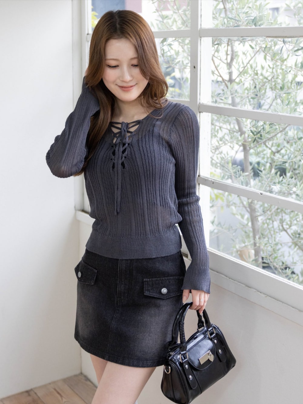 グレー系のブーツ、ブラック系のハンドバッグ、グレー系のニット/セーターを着用したレディースの春コーディネートの5枚目の写真