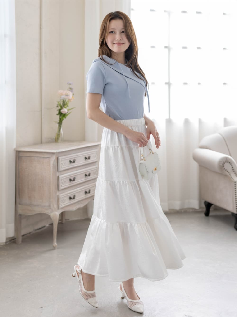 ホワイト系のスカート、ホワイト系のパンプス、ブルー系のTシャツ/カットソーを着用したレディースの春コーディネートの2枚目の写真