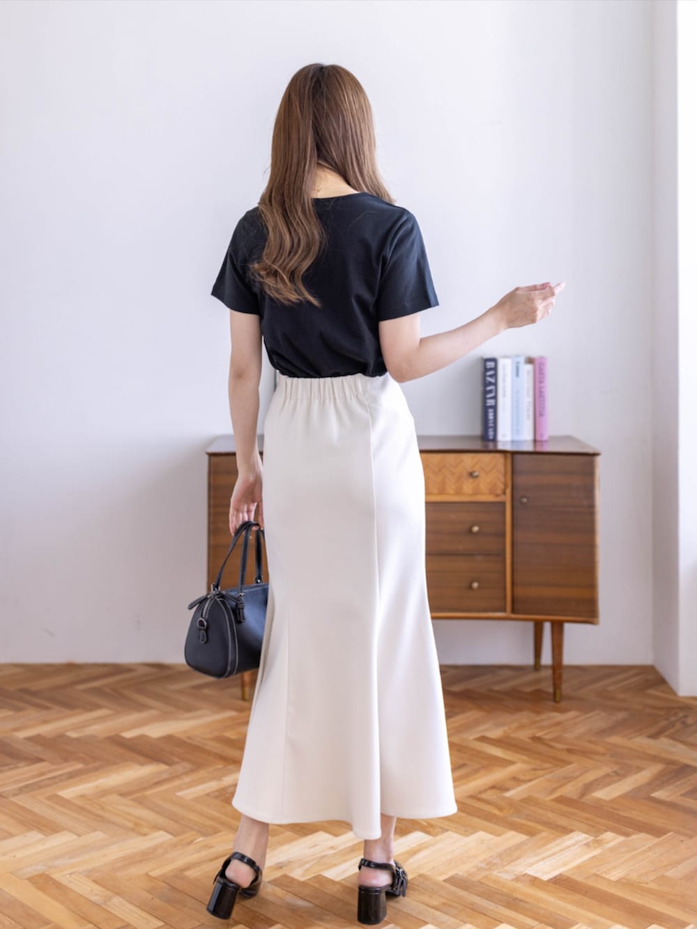 ブラック系のボストンバッグ、ブラック系のパンプス、ホワイト系のスカートを着用したレディースの春コーディネートの2枚目の写真