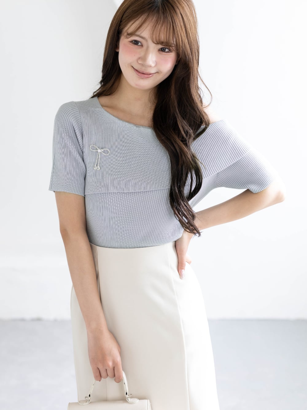 ホワイト系のスカート、ホワイト系のハンドバッグ、グレー系のニット/セーターを着用したレディースの春コーディネートの5枚目の写真